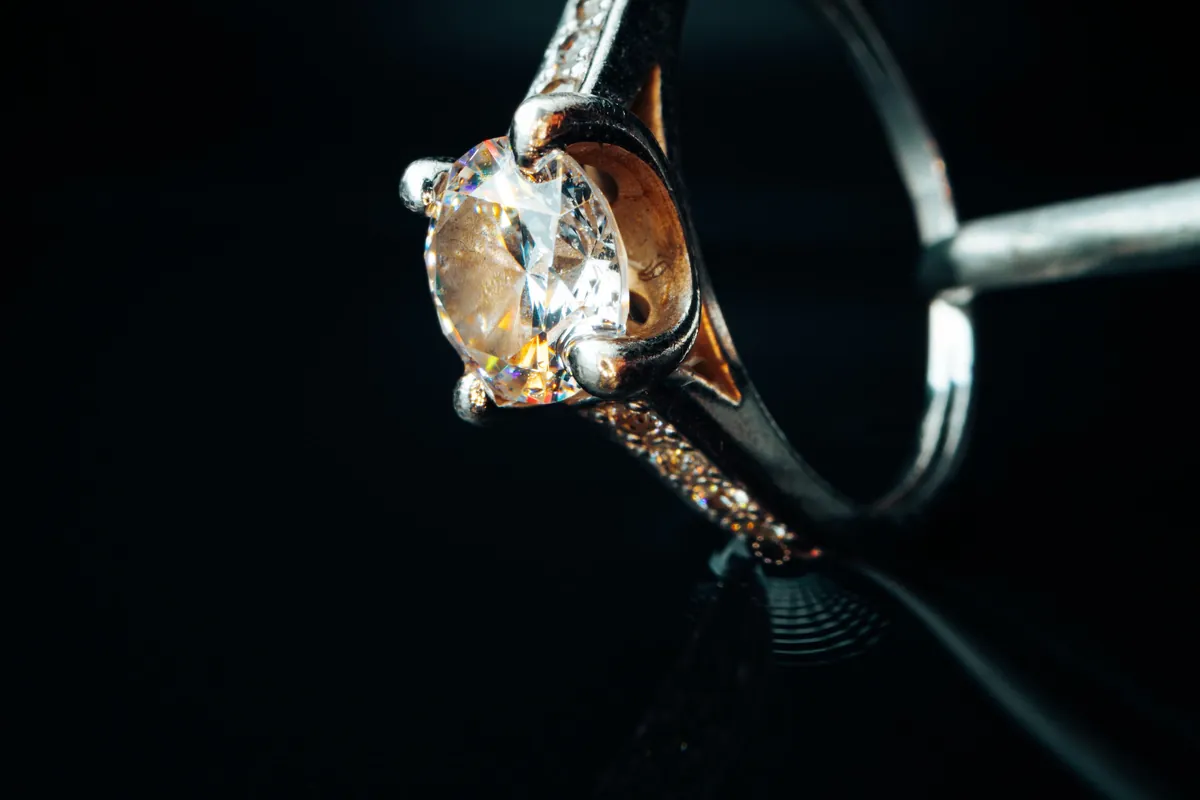 Ein Goldring mit Diamant in Nahaufnahme vor schwarzem Hintergrund