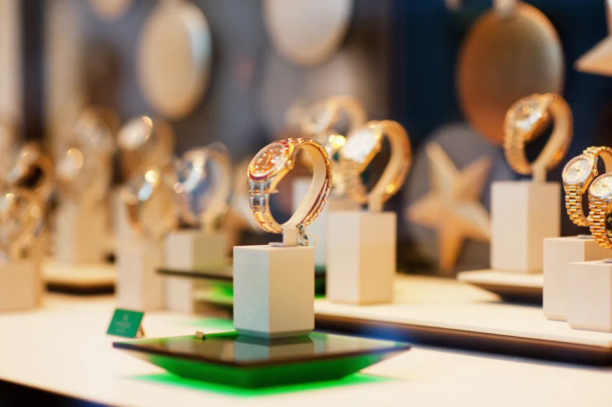 Goldene Armbanduhren auf weißen Ständern im Schaufenster eines Juweliers