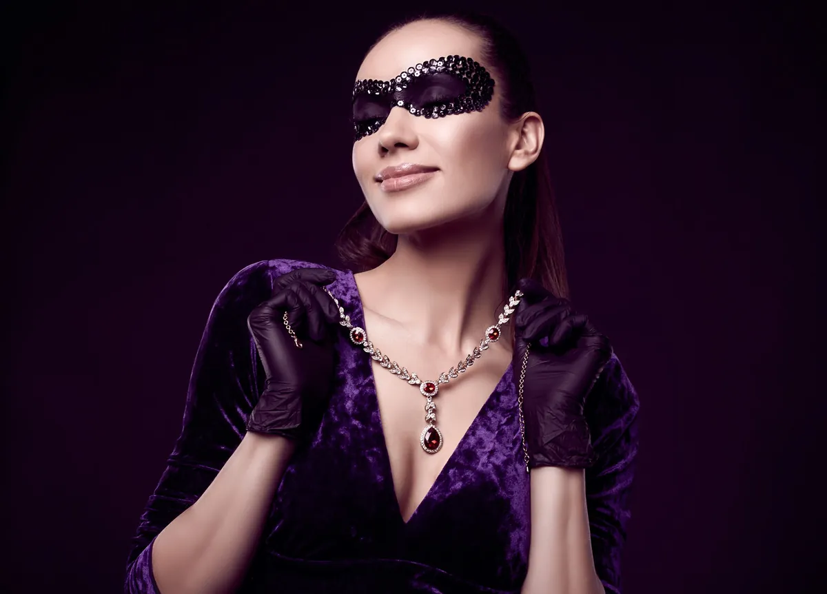 Eine Frau in violettem Samtkleid mit langen schwarzen Abendhandschuhen und Anhänger
